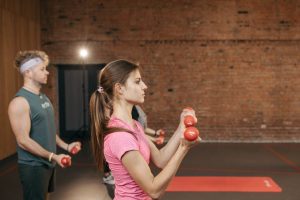 Group of adults exercising indoors with dumbbells, focused on fitness and health.