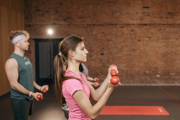 Group of adults exercising indoors with dumbbells, focused on fitness and health.