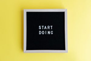 Black message board with 'Start Doing' on a bright yellow background for inspiration.